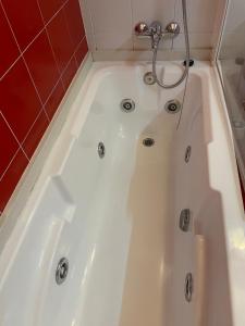a white bath tub in a bathroom with a red wall at A Ribeira do Tambre in Troitosende