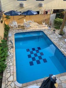 una gran piscina azul con sillas y sombrillas en Pousada Casa Hospedaria, en Paraty