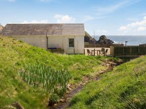 a house on a hill with the ocean in the background at Watersreach in Collieston