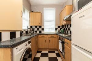 uma cozinha com armários de madeira e uma máquina de lavar e secar roupa em Lovely Suite 1 - Private Room in Eccles em Manchester