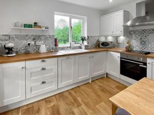 Rose Cottage في Blakemere: مطبخ بدولاب بيضاء وأرضية خشبية