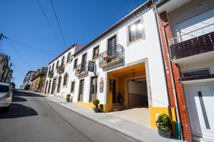 a street with white buildings and a car parked on the street at Casa do Campo AL in Caldas de São Jorge