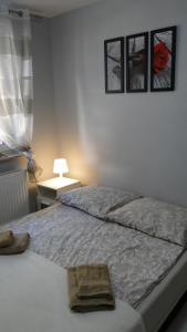 a bedroom with a bed with two pictures on the wall at Apartament Scandynawski in Kołobrzeg