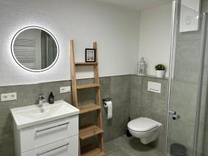 un bagno con lavandino, WC e specchio di Ferienwohnung an der Eisdiele a Freisen