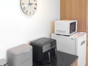 uma cozinha com um micro-ondas, uma impressora e um relógio em Hynish House em Stornoway