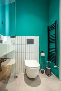 een badkamer met een wit toilet en een groene muur bij Mazi Rooms Charilaou 2,3 in Thessaloniki