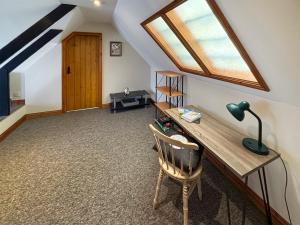 Zimmer im Dachgeschoss mit einem Schreibtisch und einem Fenster in der Unterkunft The Roost in Holme next the Sea