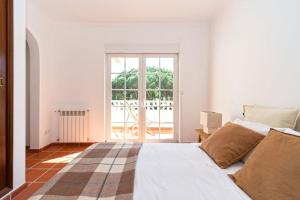 a white bedroom with a bed and a large window at Praia del Rey Golf & Beach Resort - T3 in Amoreira