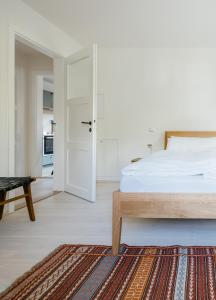 ein weißes Schlafzimmer mit einem Bett und einem Teppich in der Unterkunft Haus Herzogstand - Ferienwohnungen in Kochel am See in Kochel