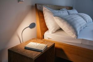 ein Bett mit einem Tisch mit einer Lampe und einem Buch in der Unterkunft Haus Herzogstand - Ferienwohnungen in Kochel am See in Kochel