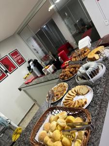 a counter with several plates of bread and pastries at Hotel Vitrine in Goiânia