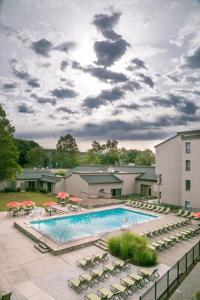 a swimming pool with chairs and umbrellas next to a building at Heritage Hotel, Golf, Spa & Conference Center, BW Premier Collection in Southbury