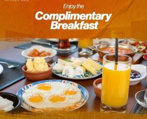una mesa cubierta con platos de desayuno y un vaso de zumo de naranja en Clifton Lodge Boutique Hotel en Karachi