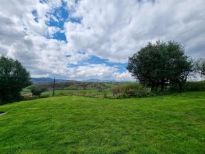 um grande campo verde com árvores e um céu nublado em Cefn Canol em Betws-y-coed