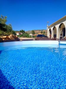 una piscina de agua azul frente a una casa en Casa rural Rocío - Caminito del Rey, en Valle de Abdalajís