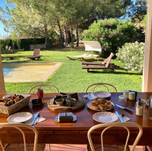 una mesa de madera con platos de comida. en Le Patio, chambres d hôtes pour adultes en Camargue, possibilité de naturisme à la piscine,, en Aimargues