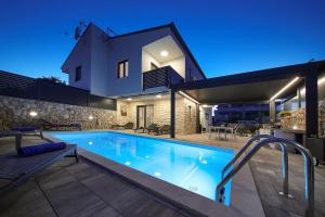 a swimming pool in front of a house at night at Holiday house ZOROO with private pool in Sveti Anton