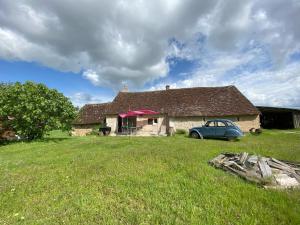 an old house with a car parked in the yard at Au Chêne Gauthier in Pouillé
