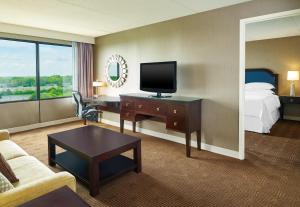 Habitación de hotel con cama y escritorio con TV. en Sheraton Lisle Naperville Hotel, en Lisle