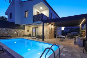 a villa with a swimming pool in front of a house at Holiday house ZOROO with private pool in Sveti Anton