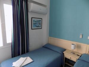 - une petite chambre avec un lit bleu et une fenêtre dans l'établissement Hostal Villa Maruja, à El Arenal