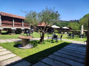a patio with a table and chairs and a tree at A Ribeira do Tambre in Troitosende