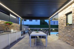 a kitchen and dining area with a white table and chairs at Holiday house ZOROO with private pool in Sveti Anton +32 photos