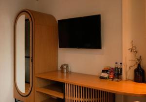 a living room with a tv and a wooden shelf at Nomada Hotel Origen in Medellín