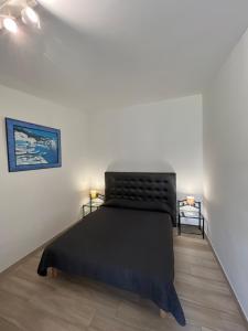 1 dormitorio con cama negra en una pared blanca en Hotel les jardins Sta Giulia avec piscine, en Porto Vecchio