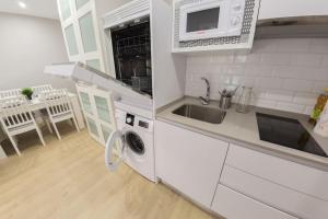 uma cozinha branca com um lavatório e uma máquina de lavar roupa em Nuñez de Arce em Toledo