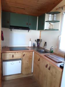 a kitchen with green cabinets and a white dishwasher at Cap d'Agde chalet vue sur la mer in Agde