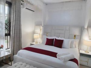a bedroom with a large white bed with red pillows at 3 BDR Luxurious Villa in Milimani Kisumu in Kisumu