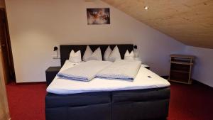 a bedroom with a bed with white sheets and pillows at Pension Bergheim in Tannheim