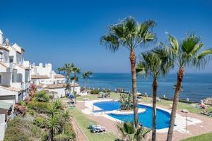 Una vista de un resort con palmeras y el océano. en PL- Beachfront seaview and frontline beach, en Mijas Costa