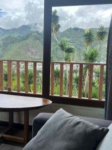 een kamer met een balkon met uitzicht op palmbomen bij Bubucoca Residence in Baños