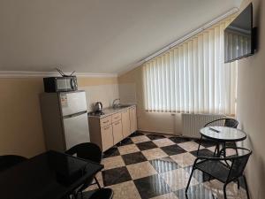 a kitchen with a refrigerator and a table and chairs at Guesthouse Emilya in Kutaisi