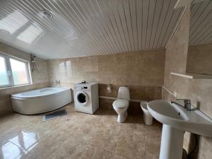 a bathroom with a tub and a sink and a washing machine at Guesthouse Emilya in Kutaisi