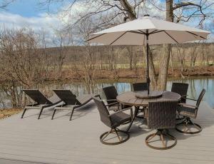 une table et des chaises avec un parasol sur une terrasse dans l'établissement Brand New House with Large Porch in Lake Katrine, à Lake Katrine