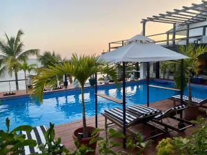 a swimming pool with two lounge chairs and an umbrella at Villa Condesa Del Mar in Contadora