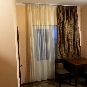 a room with a window with a curtain and a table at Hotel Premium in Ureki