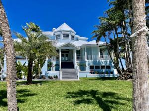une maison blanche avec des palmiers devant elle dans l'établissement 3891 Bayside, à Fort Myers Beach