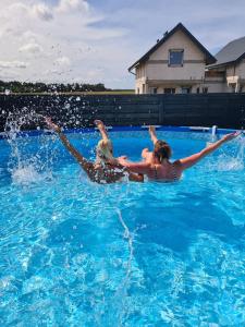 dos personas en una piscina en el agua en Domki Leśne Zacisze - Domki z basenem, en Jastrzębia Góra