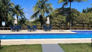 a pool with chairs and umbrellas and palm trees at Casa da Sorte in Camacari