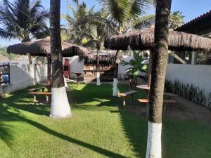 einen Garten mit Palmen, Tischen und einem Strohschirm in der Unterkunft Pousada Robijn in Cabo de Santo Agostinho