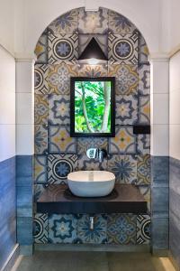 baño con lavabo y pared de azulejos en Villa Touch of Dutch en Tangalle