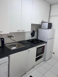 a kitchen with white cabinets and a sink and a refrigerator at Appartement avec jardin - Le Citronnier in Menton