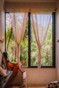 a woman sitting on a hammock in front of a window at Casa Ambar Tulum - Great Location in Tulum