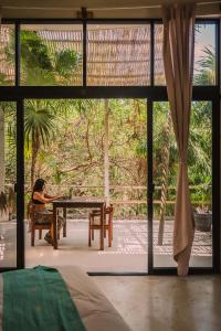 a woman sitting at a table in front of a window at Casa Ambar Tulum - Great Location in Tulum