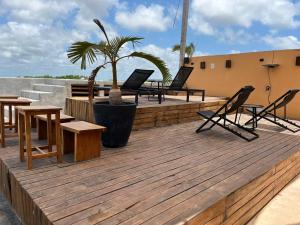 a wooden deck with chairs and a palm tree on a roof at Nuee Hotel & Beach Club in Tulum