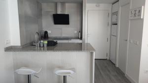 a kitchen with a counter and two stools at MIRADOR PLAYA Torrox-1ª línea playa con piscina - Deluxe in Torrox Costa